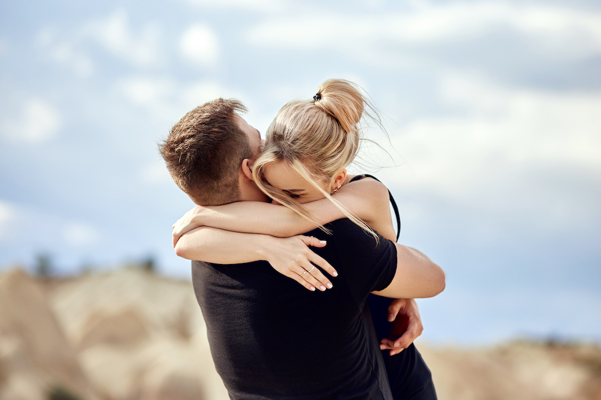 A couple embracing on a picturesque mountaintop, symbolizing a romantic marriage proposal.